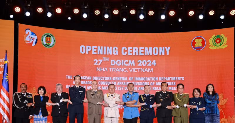 ASEAN directors-general of immigration departments and heads of consular affairs divisions hold hands at the event. (Photo: VNA)