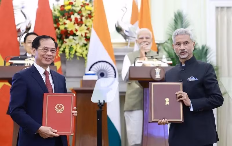 Leaders of the foreign ministries of Vietnam and India exchange an agreement between their governments allowing family members of diplomatic and consular staff to work for income. (Photo: VNA)