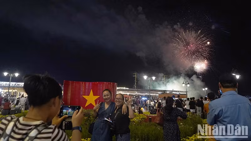 Many people excitedly use their phones to record the fireworks shining brightly in the city sky.