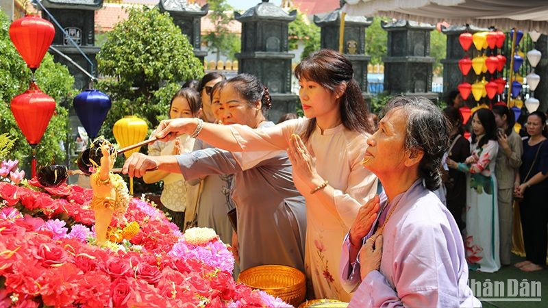 Participants perform the traditional ritual of bathing the Buddha at the ceremony.