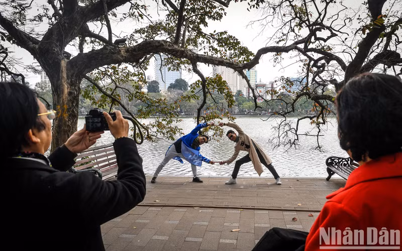 Two young men dressed in Ao Dai created a cute pose in front of Hoan Kiem Lake. Two young men dressed in Ao Dai created a cute pose in front of Hoan Kiem Lake.