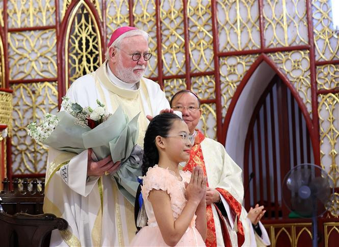 A girl presents flowers to Archbishop Paul Richard Gallagher, the 's Secretary for Relations with States and International Organisations. (Photo: VNA)