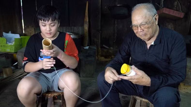 Lo Van Chien teaches his descendant the technique of making singing tubes for ‘hat ong’ singing
