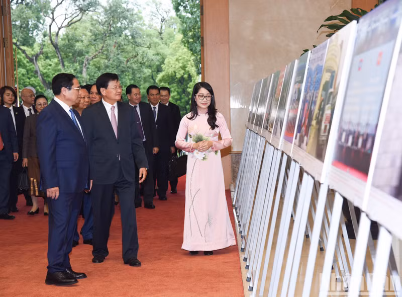 Prime Minister Pham Minh Chinh and Party General Secretary and President of Laos Thongloun Sisoulith admire photos on the outcomes of diplomatic ties between the two countries.