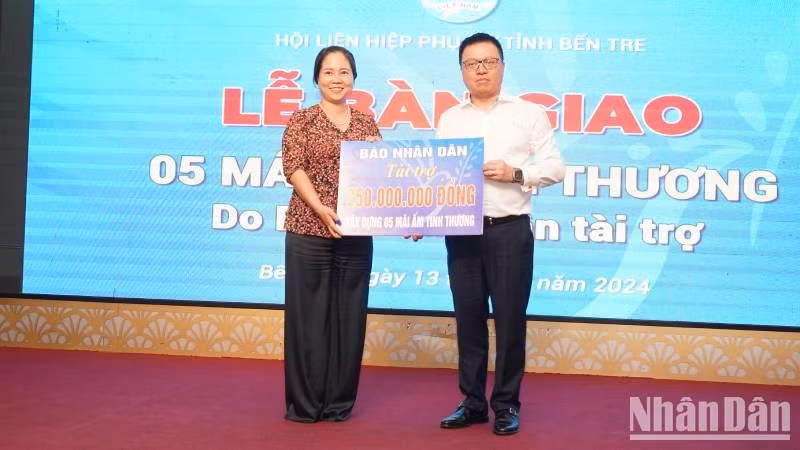 Nhan Dan Newspaper Editor-in-Chief Le Quoc Minh hands over the funding of construction of five social houses to a representative of the Ben Tre provincial Women’s Association.