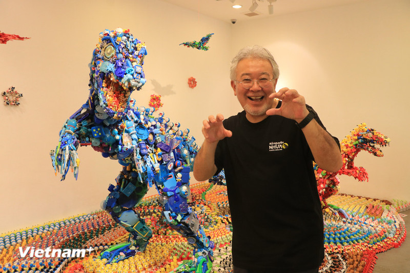 Artist Hiroshi Fuji poses in front of his works at the exhibition (Photo: VN+)
