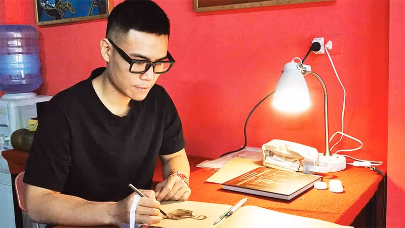 Artist Chu Nhat Quang working on a lacquer painting titled “The Path of Uncle Ho” measuring 4m by 9m