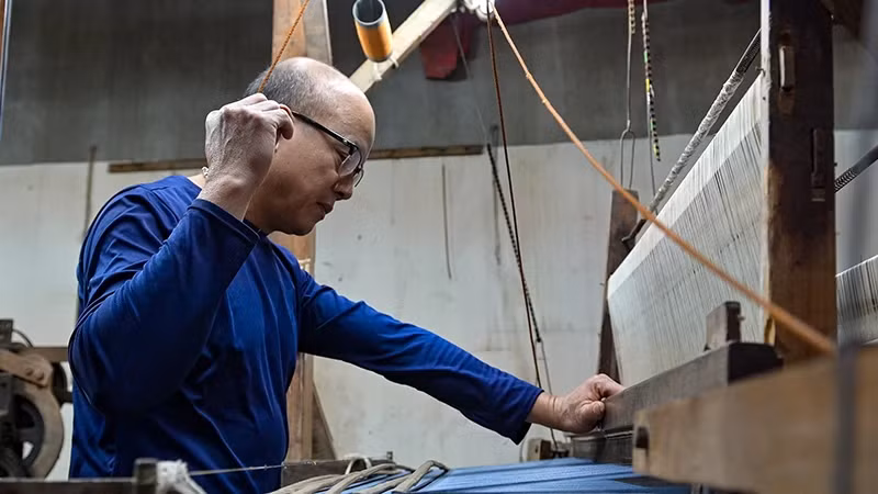 Artisan Le Dang Toan working on a traditional loom to make hand-woven silk. (Photo: THE DAI)
