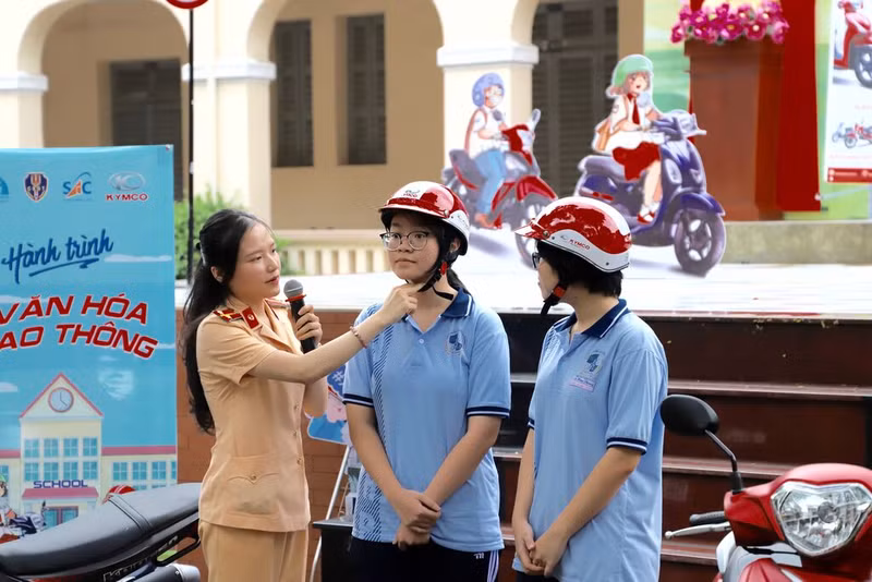 A policewoman instructs students on wearing a helmet (Photo: VNA)