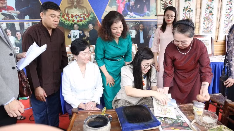 The spouse of Prime Minister Pham Minh Chinh, Le Thi Bich Tran, and delegates make Dong Ho folk paintings during their visit to Bac Ninh on April 21. (Photo: VNA)