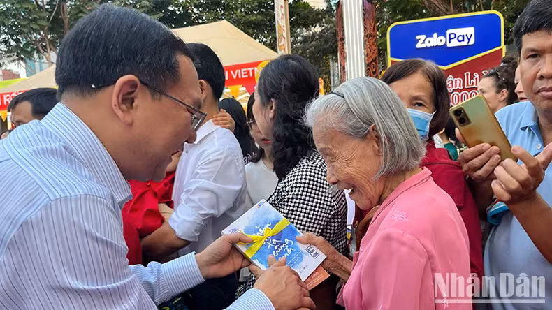 Director of the municipal Department of Information and Communications, Lam Dinh Thang, offers books to tourists as Tet gifts.