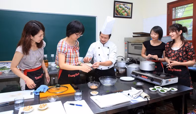 Teachers from Hoa Sua Technical School of Economics and Tourism instruct international visitors in preparing traditional Vietnamese dishes. (Photo: Anh An)