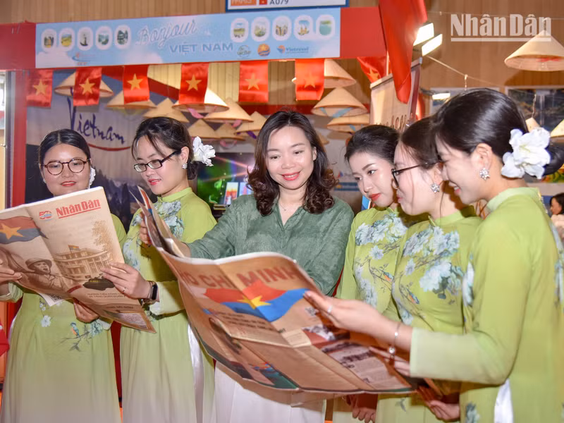 Minister Counsellor Pham Thi Kim Yen from the Vietnamese Embassy in France, along with Vietnamese students, view the special edition, which includes detailed information on the Ho Chi Minh Campaign and the iconic moment of the liberation army capturing the Independence Palace.