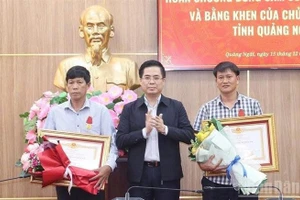 Chairman of the Quang Ngai provincial People's Committee Nguyen Hoang Giang (centre) presents the State President's Bravery Order to two citizens of Ly Son special zone on December 15. (Photo: NDO)