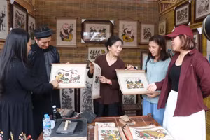 A Dong Ho folk painting artisan introduces his works to visitors at the festival “Returning to the Heritage Region – 2026”.