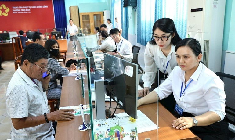 Handling administrative procedures at the Public Administration Service Center of Tran Bien Ward, Dong Nai Province. (Photo: THIEN VUONG) 080725-hieu-qua-tu-mo-hinh-cq-dia-phuong-2-cap-2.jpg