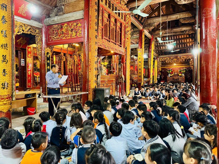 Pupils from Sai Dong Urban Area Primary School learn about Le Mat Communal House (Viet Hung Ward), a historical site near their residential area. (Photo: GIANG NAM) 070825-sau-re-ben-goc-5.jpg