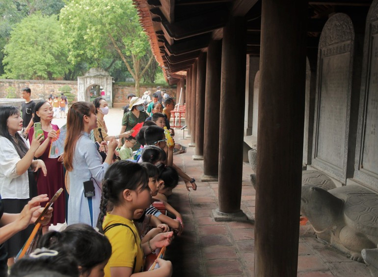 Pupils listen to stories about the scholarly tradition of Thang Long – Ha Noi beside the Doctoral Steles at the Temple of Literature – Quoc Tu Giam. (Photo: GIANG NAM) 070825-sau-re-ben-goc-3.jpg