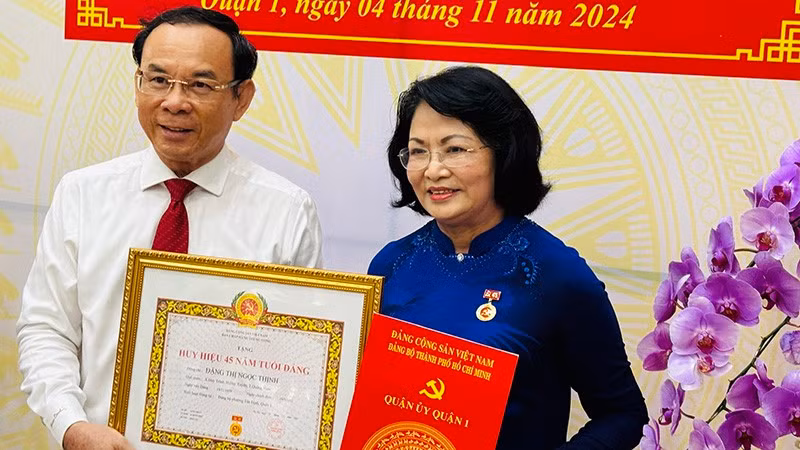 Ho Chi Minh City Party Secretary Nguyen Van Nen presents the 45-year Party membership badge to former Vice President Dang Thi Ngoc Thinh.