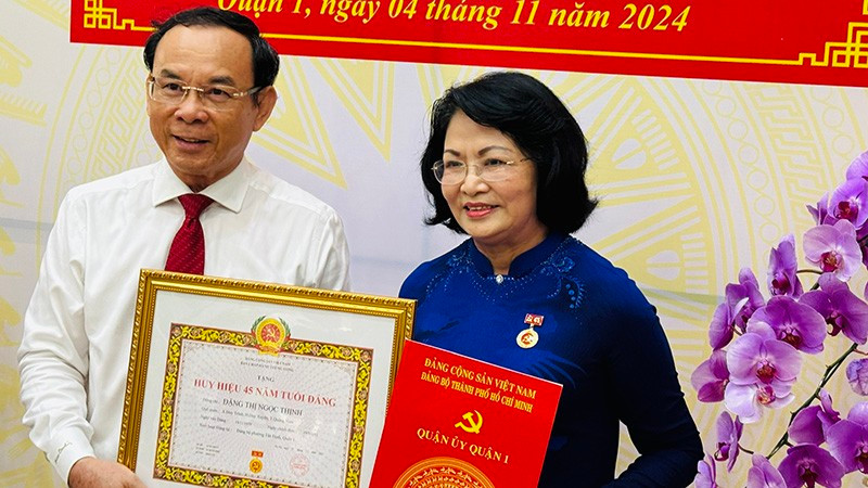 Ho Chi Minh City Party Secretary Nguyen Van Nen presents the 45-year Party membership badge to former Vice President Dang Thi Ngoc Thinh.