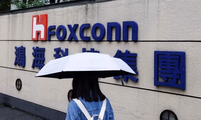 A woman carrying an umbrella walks past the logo of Foxconn outside the company's building in Taipei. (Photo: Reuters) 