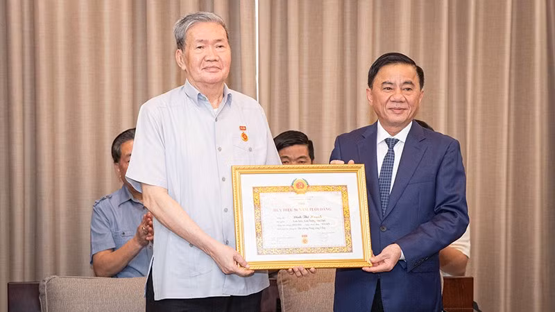 Former Permanent member of the Secretariat Dinh The Huynh (left) receives the 50-year Party membership badge.