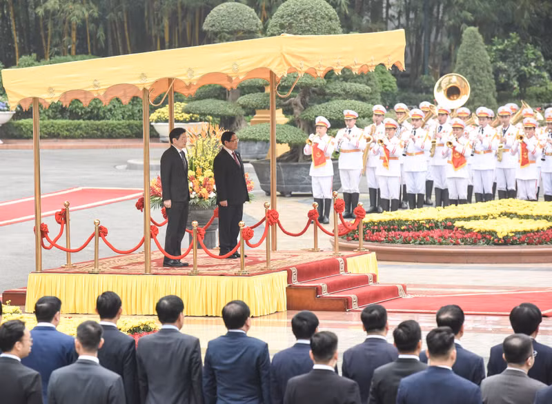 PM Pham Minh Chinh and his Singaporean counterpart Lawrence Wong salute the flags of the two countries.