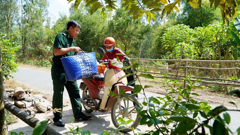 A member of the Border Guard Station at the Dinh Ba International Border Gate provides assistance to a local resident.