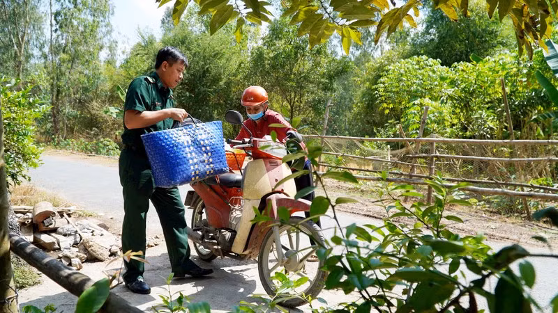 A member of the Border Guard Station at the Dinh Ba International Border Gate provides assistance to a local resident.