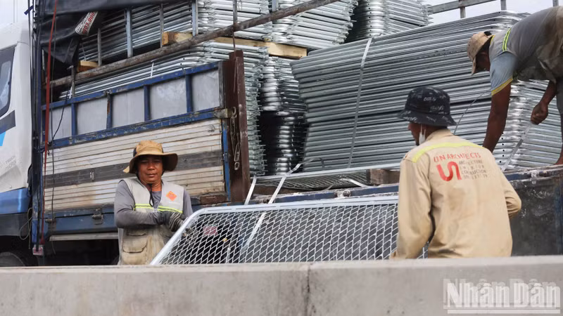 At the construction site, workers are busily setting up road barriers.