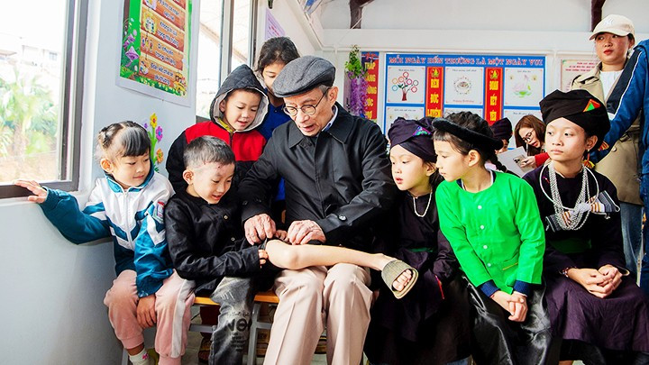 The “grandfather” Nguyen Xuan Khang inspects the scar of an orphaned child. 