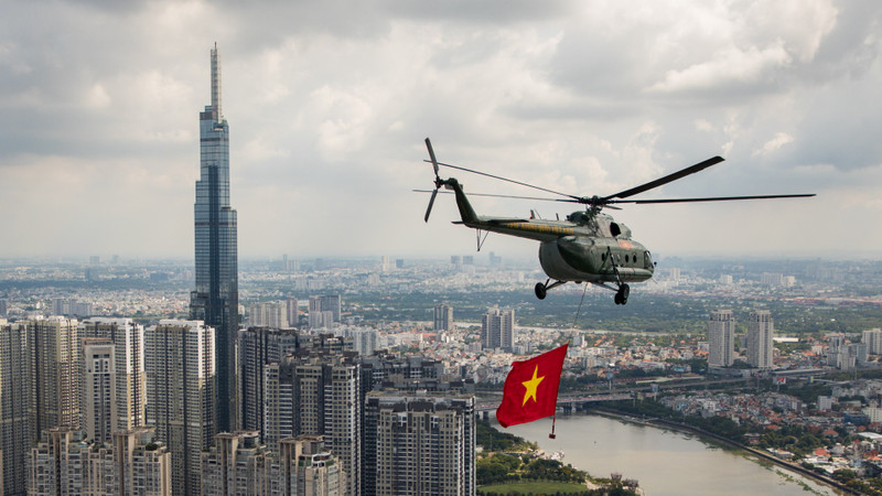 A helicopter carrying the national flag flies over Landmark 81, the tallest tower in Vietnam and a new symbol of Ho Chi Minh City’s development.