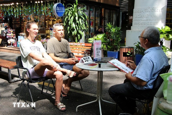 Foreign tourists enjoy a painting service in Nguyen Van Binh book street in Ho Chi Minh City. (Photo: VNA)