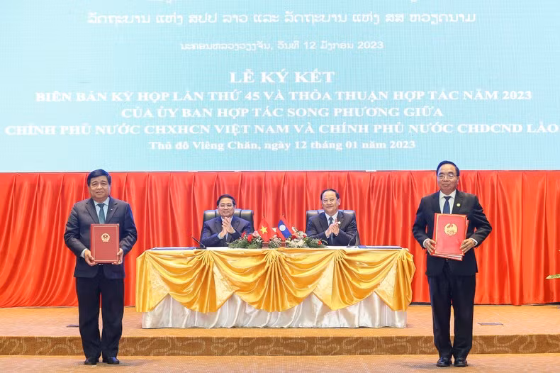 Vietnamese and Lao PMs witness the signing of documents.