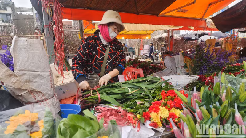A lily seller is busy wrapping one of the most sought after flowers during Tet.