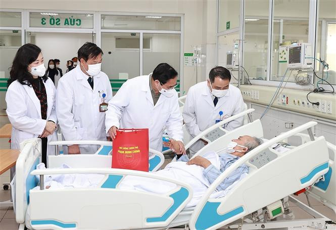 Prime Minister Pham Minh Chinh presents gift to a patient at National Hospital for Tropical Diseases. (Photo: VNA)