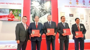 General Secretary To Lam and other Party and State incumbent and former leaders receive the book titled “Uncle Ho’s articles on Culture and Journalism by in Nhan Dan Newspaper” at the Nhan Dan exhibition’s pavilion. 
