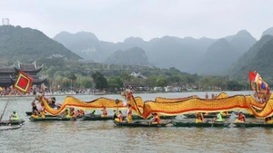 A procession of dragon boats carries sacred water from Tam Chuc Lake to Ngoc Mountain. (Photo: DAO PHUONG)