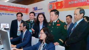 General Nguyen Trong Nghia (standing, front, second from right) visits Viet Nam News Agency reporters covering the 14th National Party Congress on January 20. (Photo: VNA)