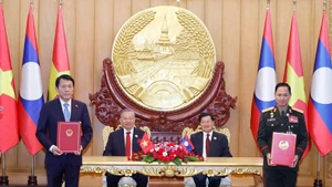 Vietnamese Party General Secretary To Lam (second, left), and Party General Secretary and President of Laos Thongloun Sisoulith witness the exchange of memorandum of understanding (MoU) on cooperation between the Vietnamese Ministry of Public Security and the Lao Ministry of National Defence on building a Viet Nam - Laos friendship road. (Photo: VNA)