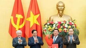 Prime Minister Pham Minh Chinh (second from left) and National Assembly Chairman Tran Thanh Man (far right) present the appointment decision and offer flowers to Nguyen Hong Dien. (Photo: VNA)