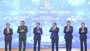 Prime Minister Pham Minh Chinh (third from right) and officials launch the Ministry of Construction’s new information technology systems at the conference on December 21. (Photo: NDO)