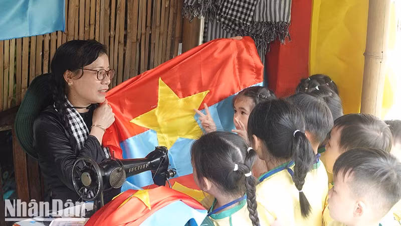 Children learning about the liberation flag during the ceremony to open exhibition. (Photo: Manh Hao)