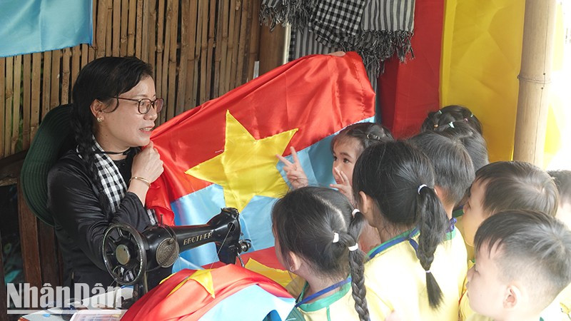 Children learning about the liberation flag during the ceremony to open exhibition. (Photo: Manh Hao)