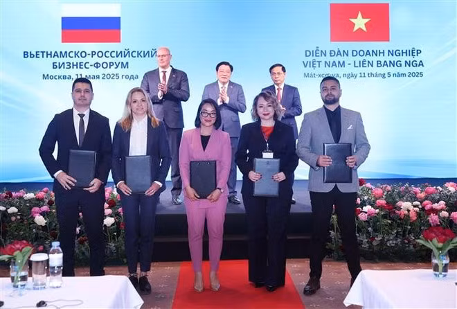 Vietnamese and Russian businesses exchange cooperation documents at the forum. (Photo: VNA)