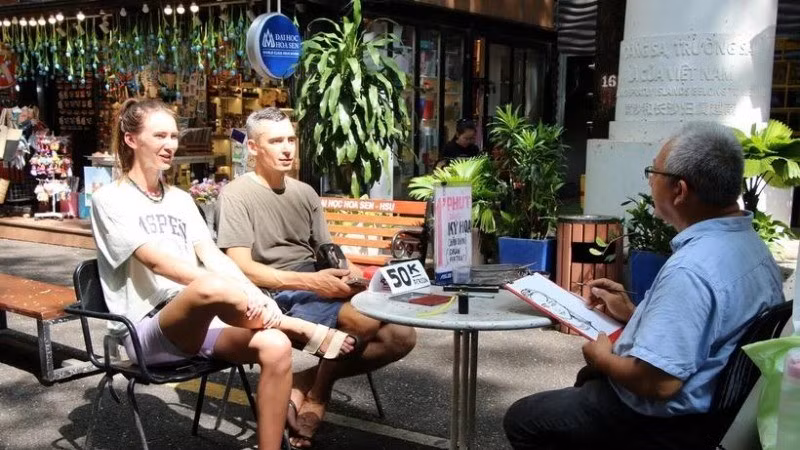 International visitors enjoy caricature drawing services on Nguyen Van Binh Book Street, a well-known tourist attraction in the heart of Ho Chi Minh City. (Photo: VNA)