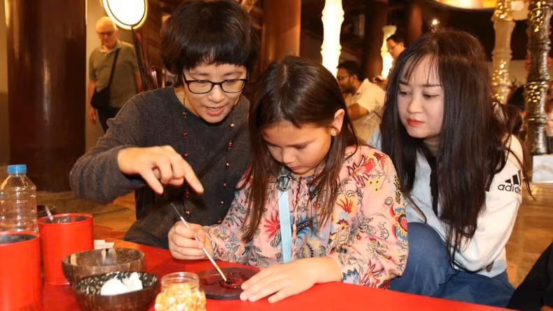 Artists and tourists creating lacquer works together at the Temple of Literature–Quoc Tu Giam