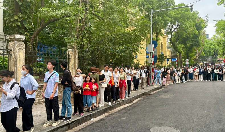 On the morning of 27 April, sisters Linh Chi and An Nhien (dressed in T-shirts featuring the red flag with a yellow star) patiently queued for their turn to experience Nhan Dan’s special newspaper products. (Photo: NDO)