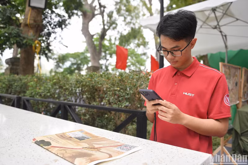 Dao Quang Duc experiences scanning QR codes on the special supplement by Nhan Dan Newspaper. (Photo: THE DAI) Dao Quang Duc experiences scanning QR codes on the special supplement by Nhan Dan Newspaper. (Photo: THE DAI)