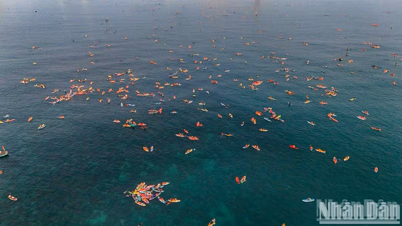 The sea glistens with colourful paddleboards.